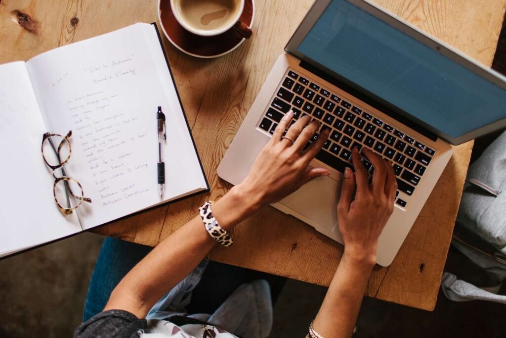 A person typing on a laptop with research notes, symbolizing a freelance writer at work - work from home jobs with no startup fee