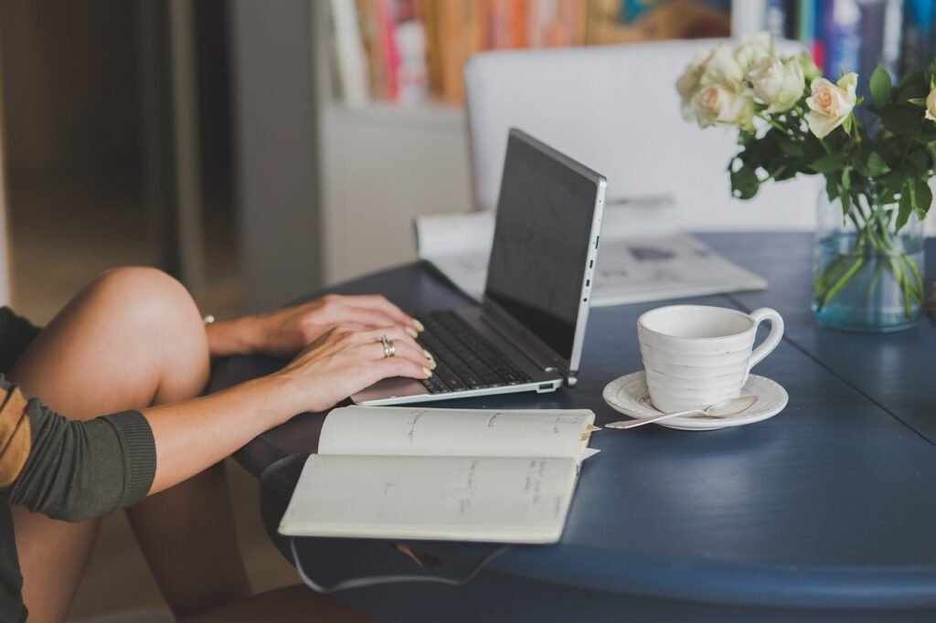 A laptop on a desk with a notebook and a coffee mug, illustrating a writer’s workspace - part time work from home jobs