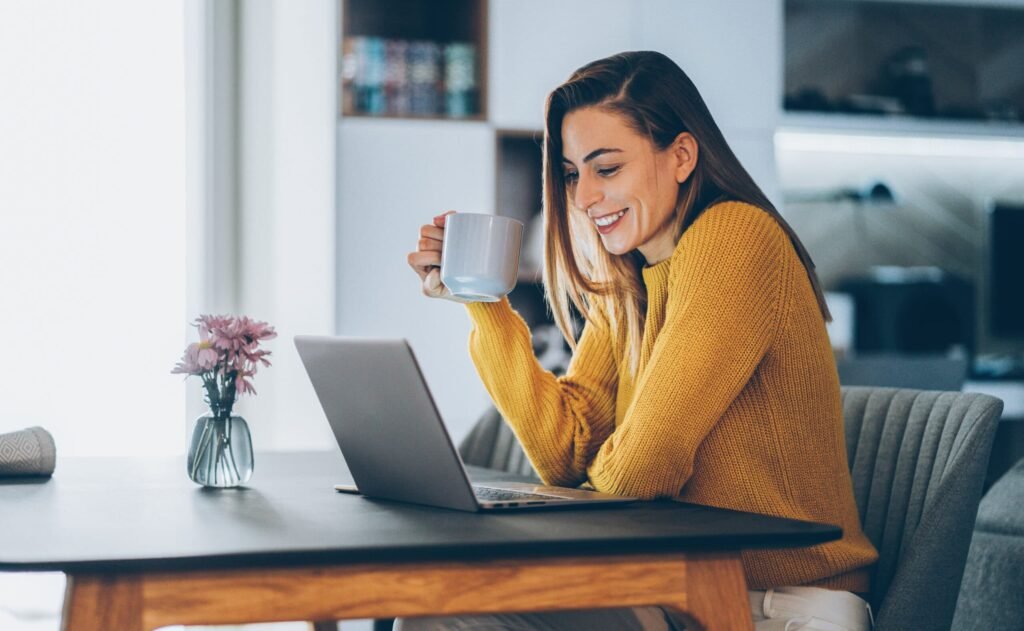 A home office setup with a laptop, coffee cup, and a notebook, representing a professional remote work environment - amazon work from home