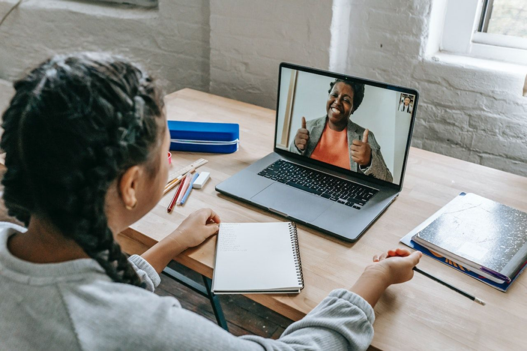 A smiling tutor with a headset, teaching a student via video call on a computer screen - entry level remote jobs