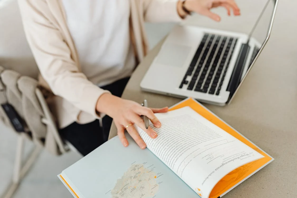 A notebook and pen next to a laptop, with someone typing an article - entry level remote jobs