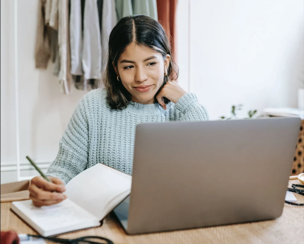 A remote worker watching an online course on their laptop with a notepad beside them - remote working jobs